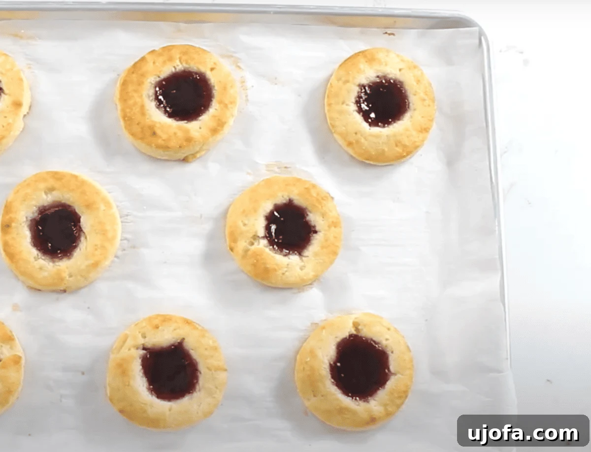 Freshly baked gluten-free Danish pastries with golden edges and jam-filled centers resting on a parchment-lined baking sheet, just out of the oven.