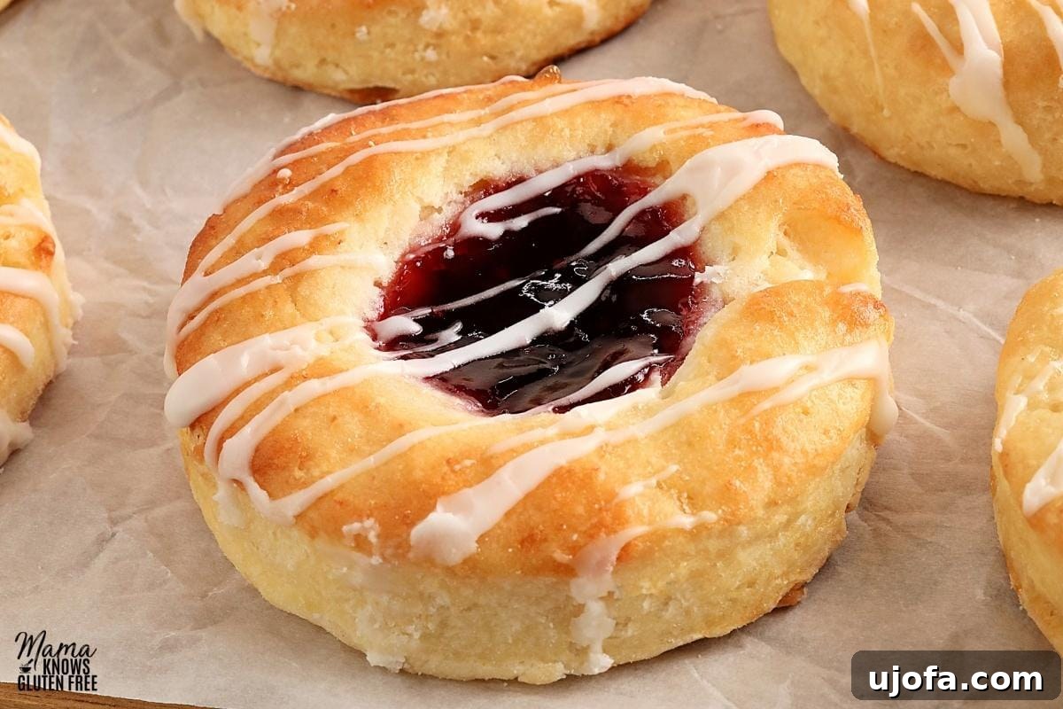 Close-up of a stack of gluten-free Danish pastries on parchment paper, showing the flaky layers and jam filling