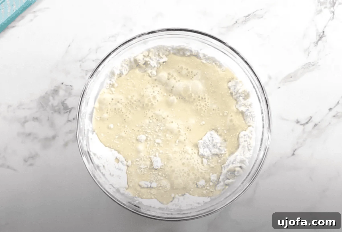 The milk and egg mixture is poured into the flour mixture, starting to form a wet, sticky dough.