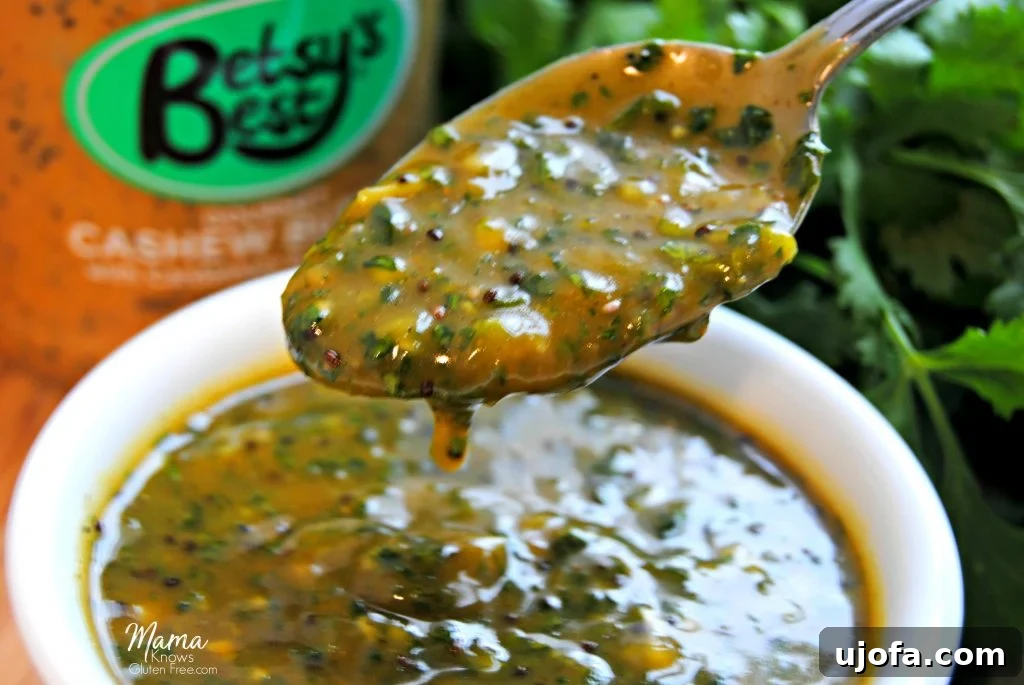 Close-up of the unique Cashew Butter Chimichurri Sauce on a spoon, with cashew butter and fresh cilantro in the background, highlighting the creamy, herbaceous texture.