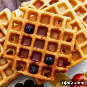 Gluten Free Brunch Delights 5 Overhead view of a stack of golden-brown gluten-free waffles, drizzled generously with maple syrup and garnished with fresh blueberries.
