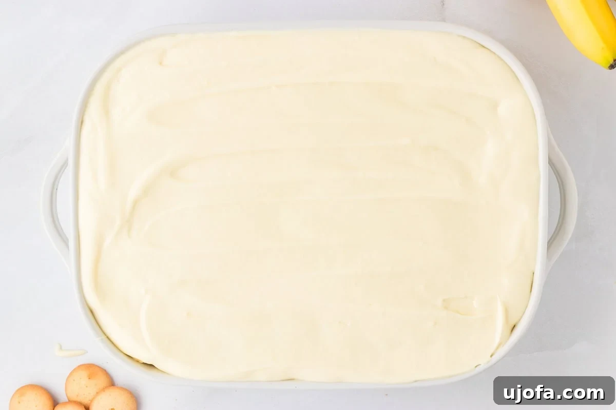 Top view of a 9x13-inch dish filled with gluten-free banana pudding, the surface smoothed out and ready for chilling or decorating.