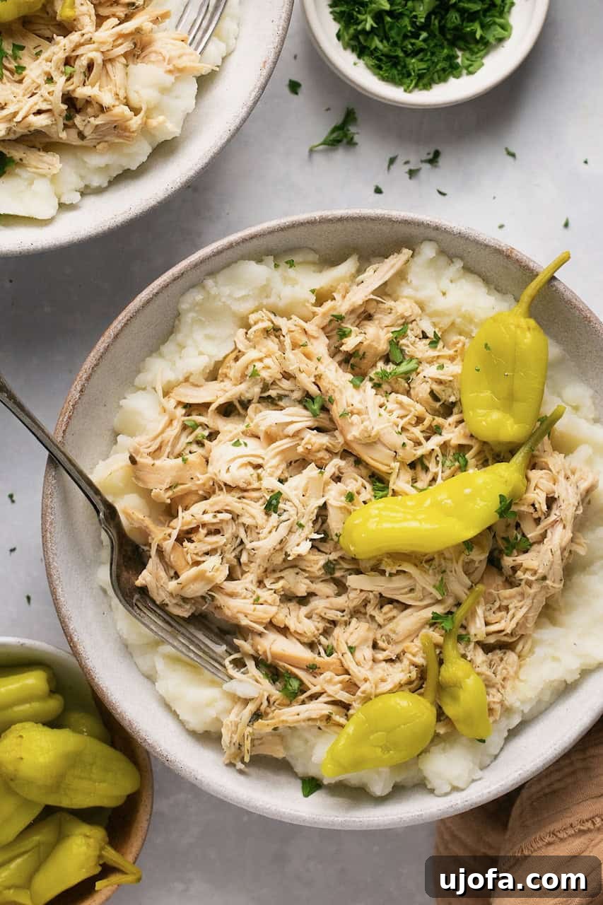 Mississippi Chicken Three Simple Variations 6 A close-up shot of Mississippi chicken served over creamy mashed potatoes in a rustic bowl, garnished with whole pepperoncini peppers.