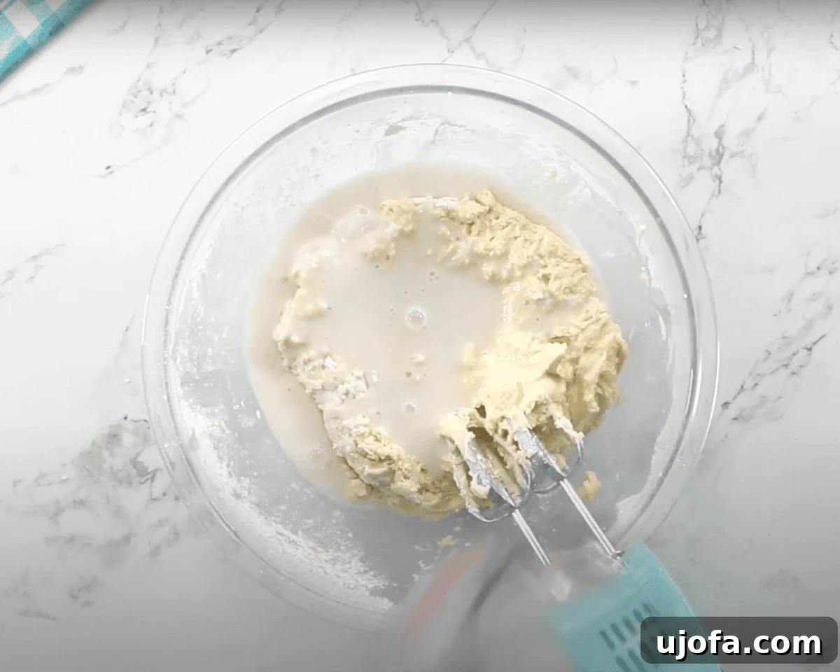 Luscious Strawberry Gluten-Free Cake 12 The batter is partially mixed, and a liquid, likely milk or buttermilk, is being added to the bowl.