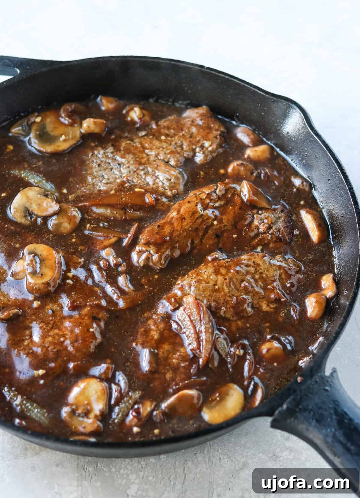 Pan-Fried Cube Steak Perfection 6 A close-up view of the tender cube steak simmering in rich mushroom and onion gravy in a 12-inch cast iron skillet, ready to be served.