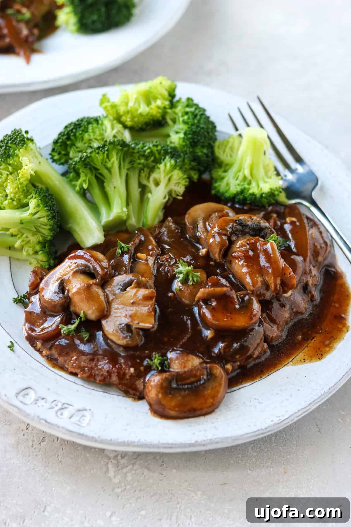 Pan-Fried Cube Steak Perfection 7 A perfectly plated cube steak with rich gravy and sautéed mushrooms, accompanied by vibrant green broccoli.