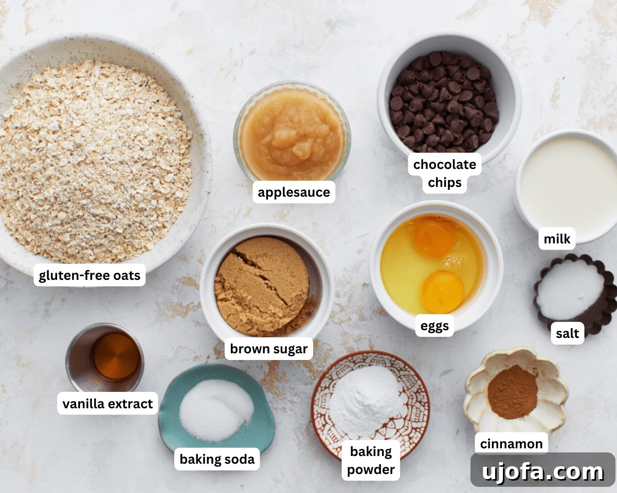 Oatmeal bars ingredients laid out on a wooden surface: eggs, applesauce, brown sugar, vanilla, milk, gluten-free oats, baking powder, baking soda, salt, cinnamon, and chocolate chips.