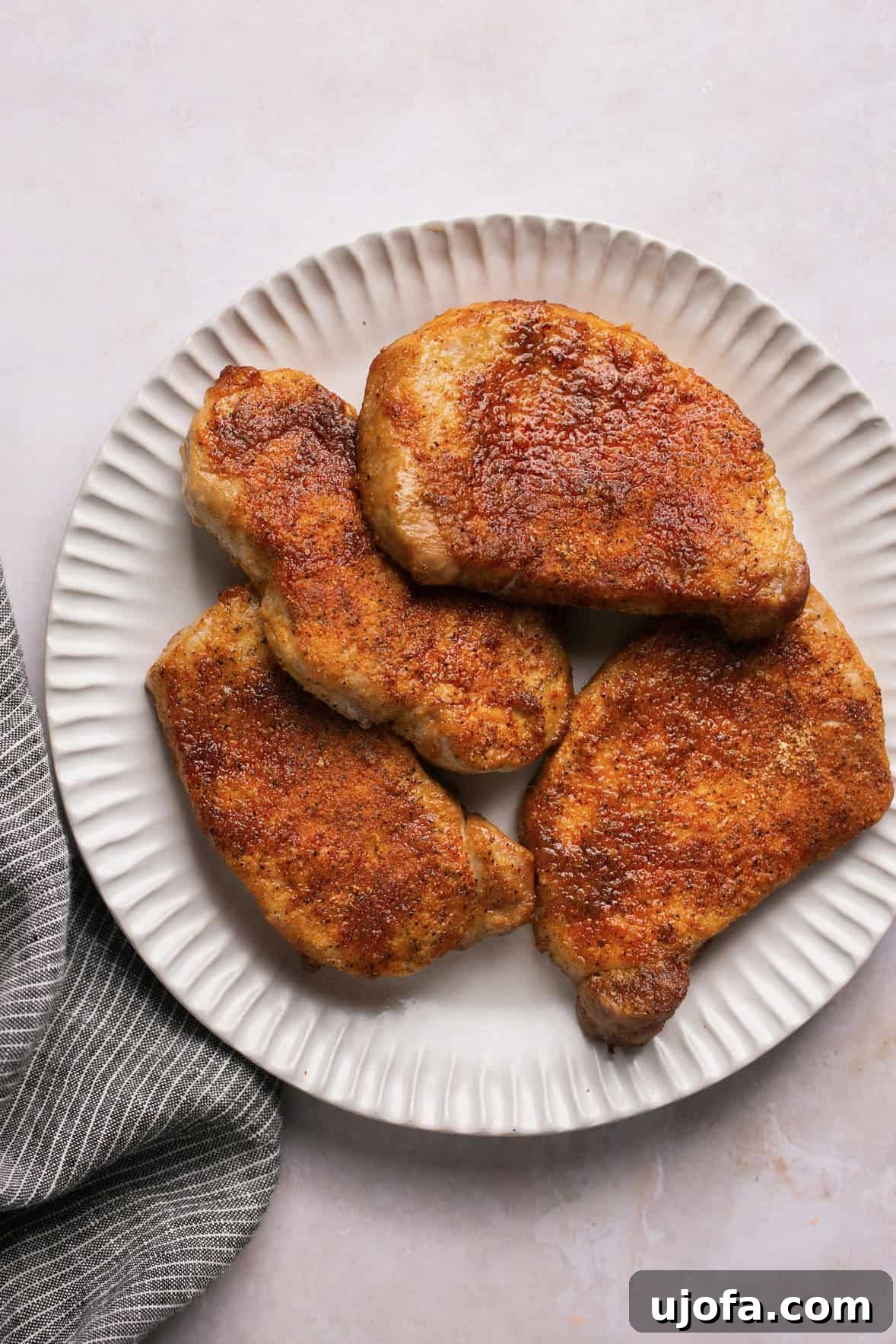 Crispy Air-Fried Pork Chops 6 Seasoned and cooked pork chops stacked on a white plate, ready to be served.
