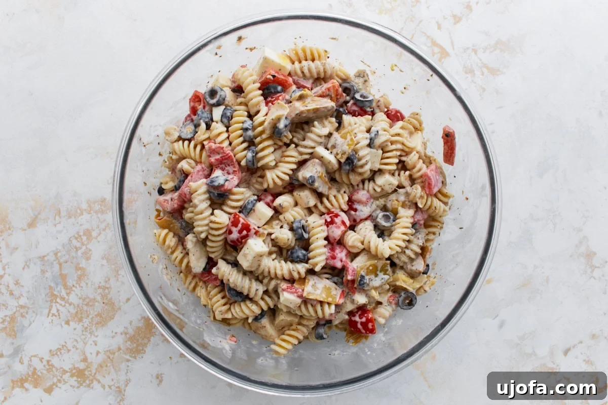 A large mixing bowl displaying the creamy Italian pasta salad ingredients fully combined and beautifully coated with the luscious dressing, highlighting a vibrant and cohesive mix.