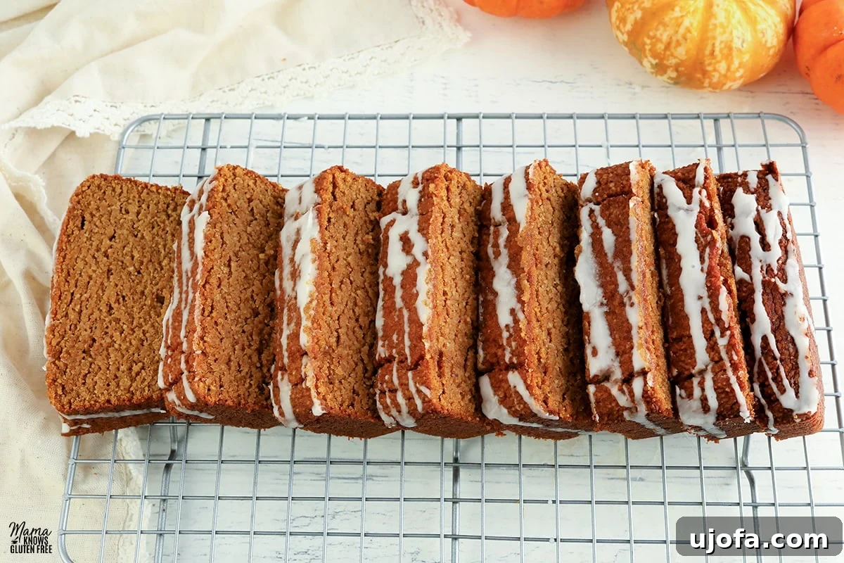 Slices of almond flour pumpkin bread drizzled with vanilla glaze on a wire cooling rack.