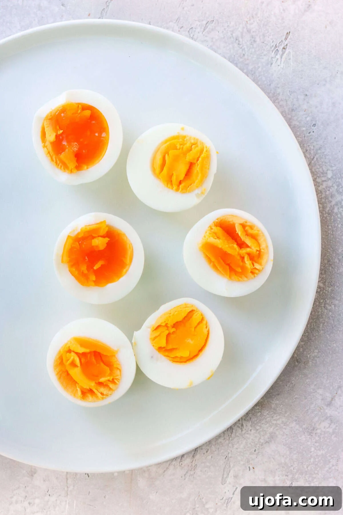 6 sliced boiled eggs on a white plate, showcasing perfect yolks.