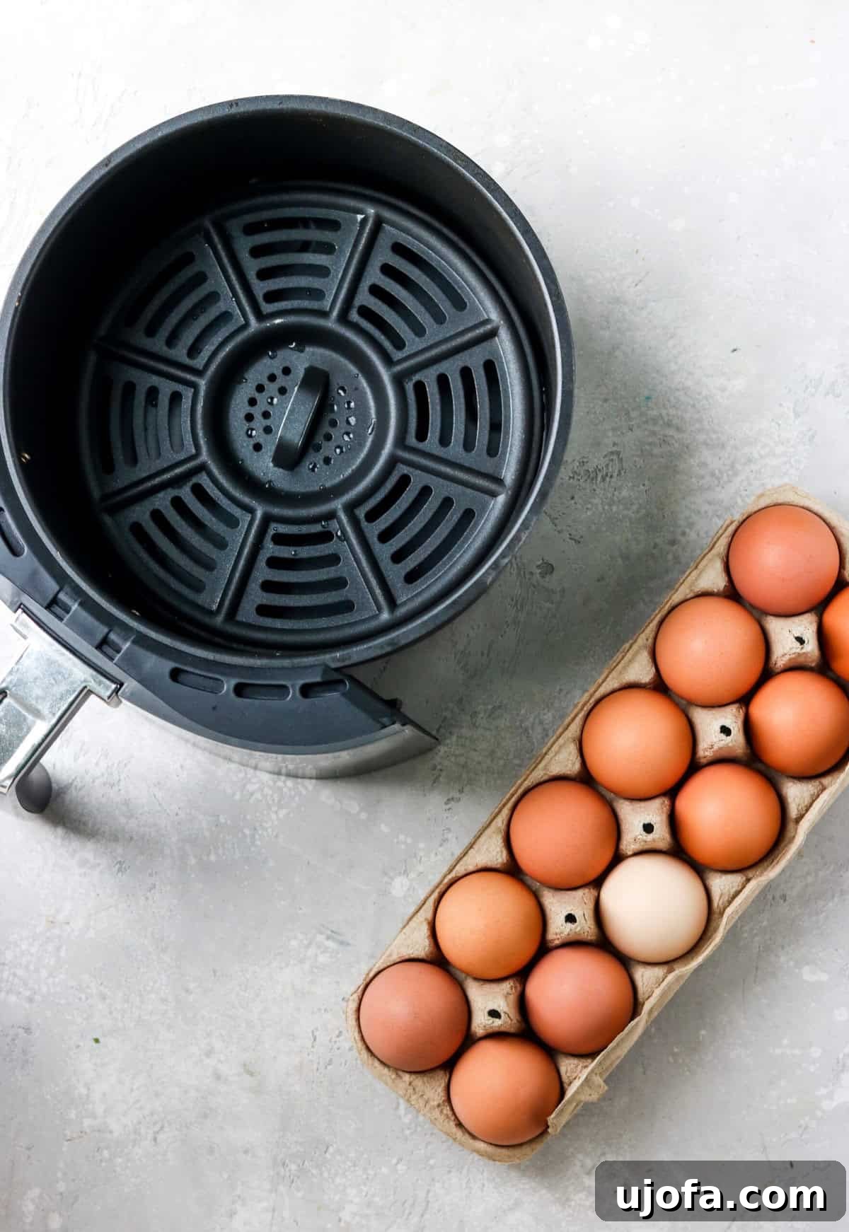 An empty air fryer basket and an open carton of fresh brown eggs.