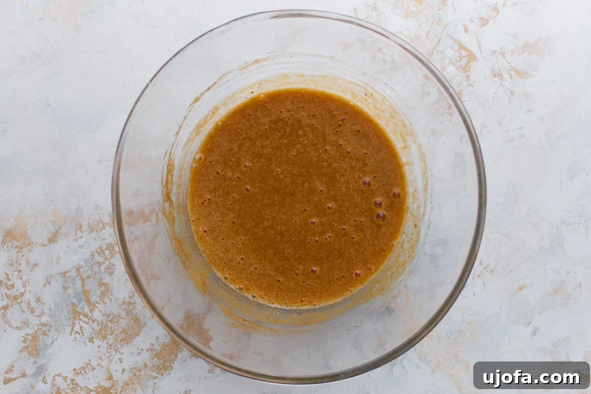 Pumpkin puree and spices mixed into the egg and sugar base, creating a light orange-brown batter.