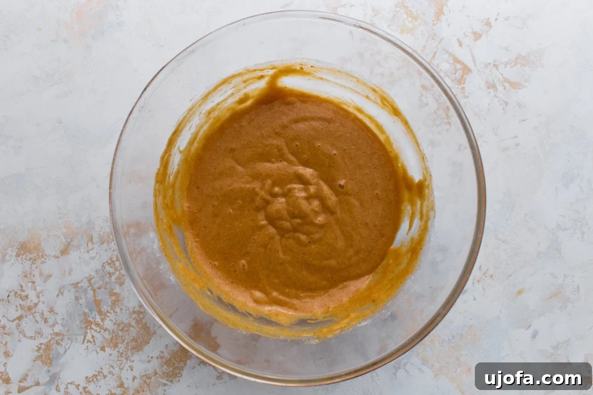 Gluten-free flour folded into the pumpkin mixture, forming a smooth, thicker cake batter.
