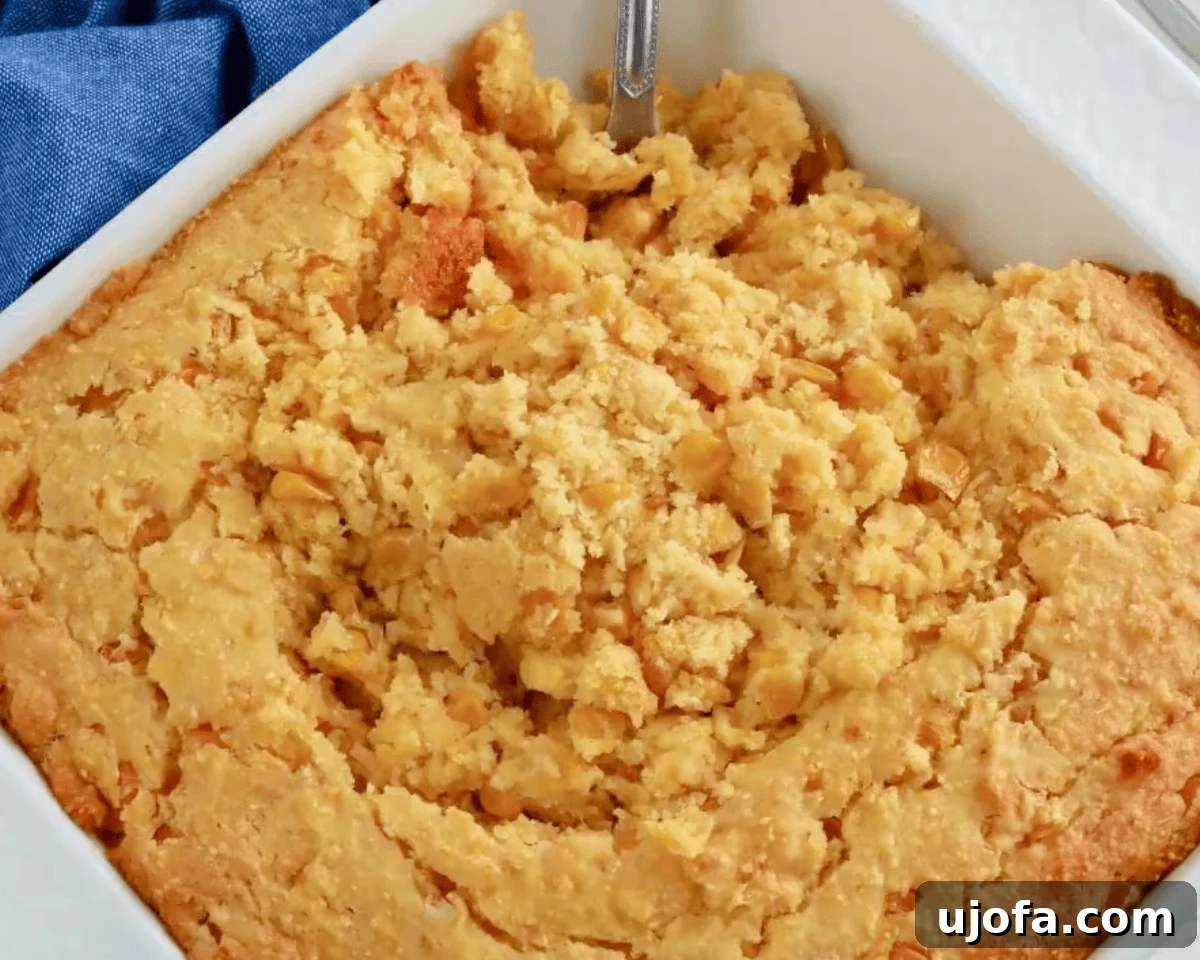 Close-up of soft, custardy gluten-free corn casserole being scooped from the baking dish, showing the tender, fluffy texture.