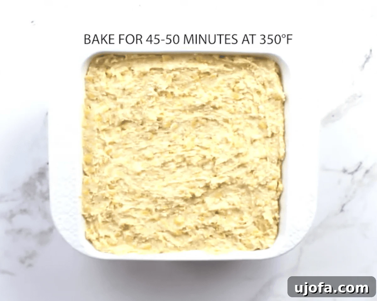 Unbaked gluten-free corn casserole batter spread evenly in a white baking dish before going into the oven.