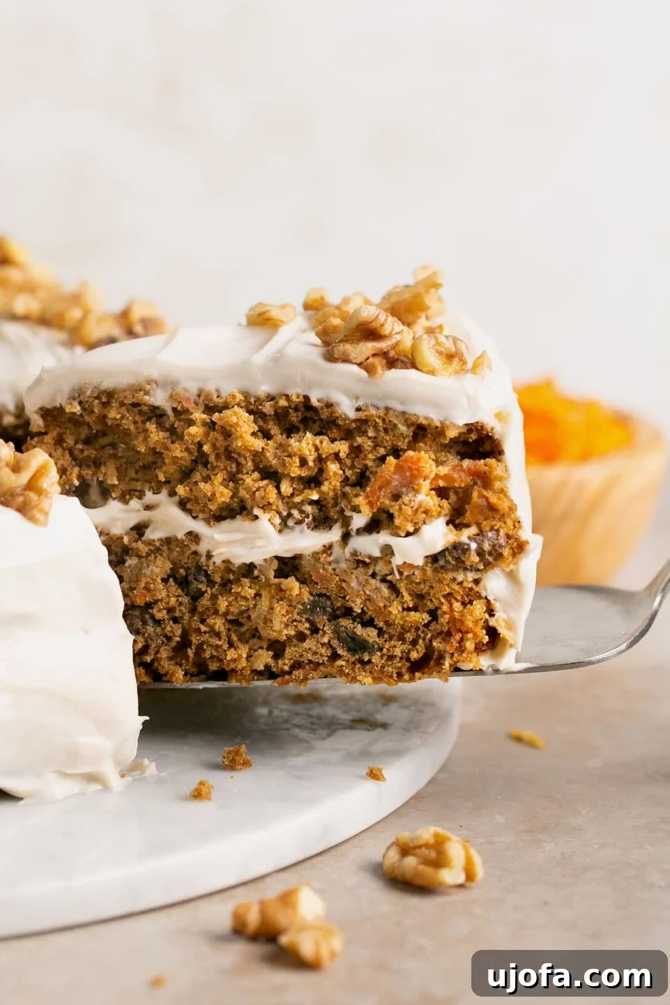 Decadent Gluten-Free Carrot Walnut Cake 2 A perfectly baked slice of gluten-free carrot cake, rich with walnuts, being lifted from the main cake with a spatula, showcasing its moist texture and inviting layers.