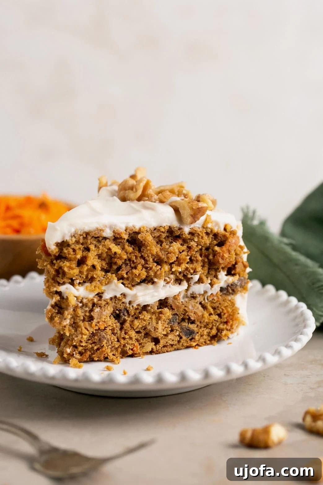 Decadent Gluten-Free Carrot Walnut Cake 9 A delectable slice of gluten-free carrot cake served on a pristine white dish, elegantly topped with chopped walnuts.