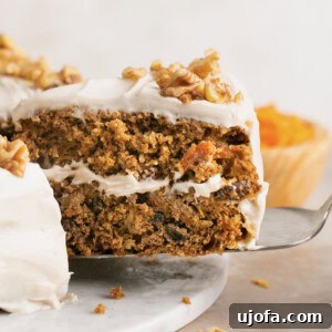 Decadent Gluten-Free Carrot Walnut Cake 10 A slice of gluten free carrot cake being pulled out of the whole cake with a spatula
