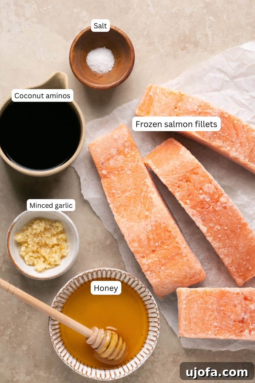 Effortless Air Fryer Salmon Straight From Frozen 3 A collection of small bowls displaying the recipe ingredients: frozen salmon fillets, fresh minced garlic, golden honey, coconut aminos, and a pinch of salt.