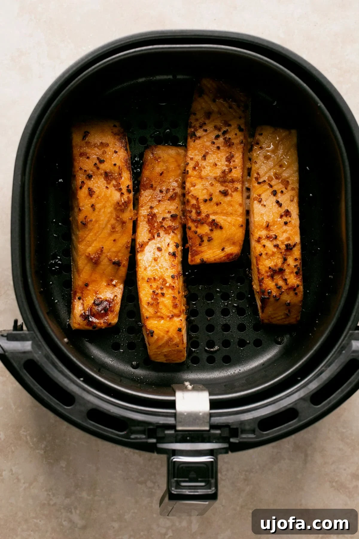 Effortless Air Fryer Salmon Straight From Frozen 5 Four golden-brown, glazed salmon fillets perfectly arranged in an air fryer basket, ready to be served.