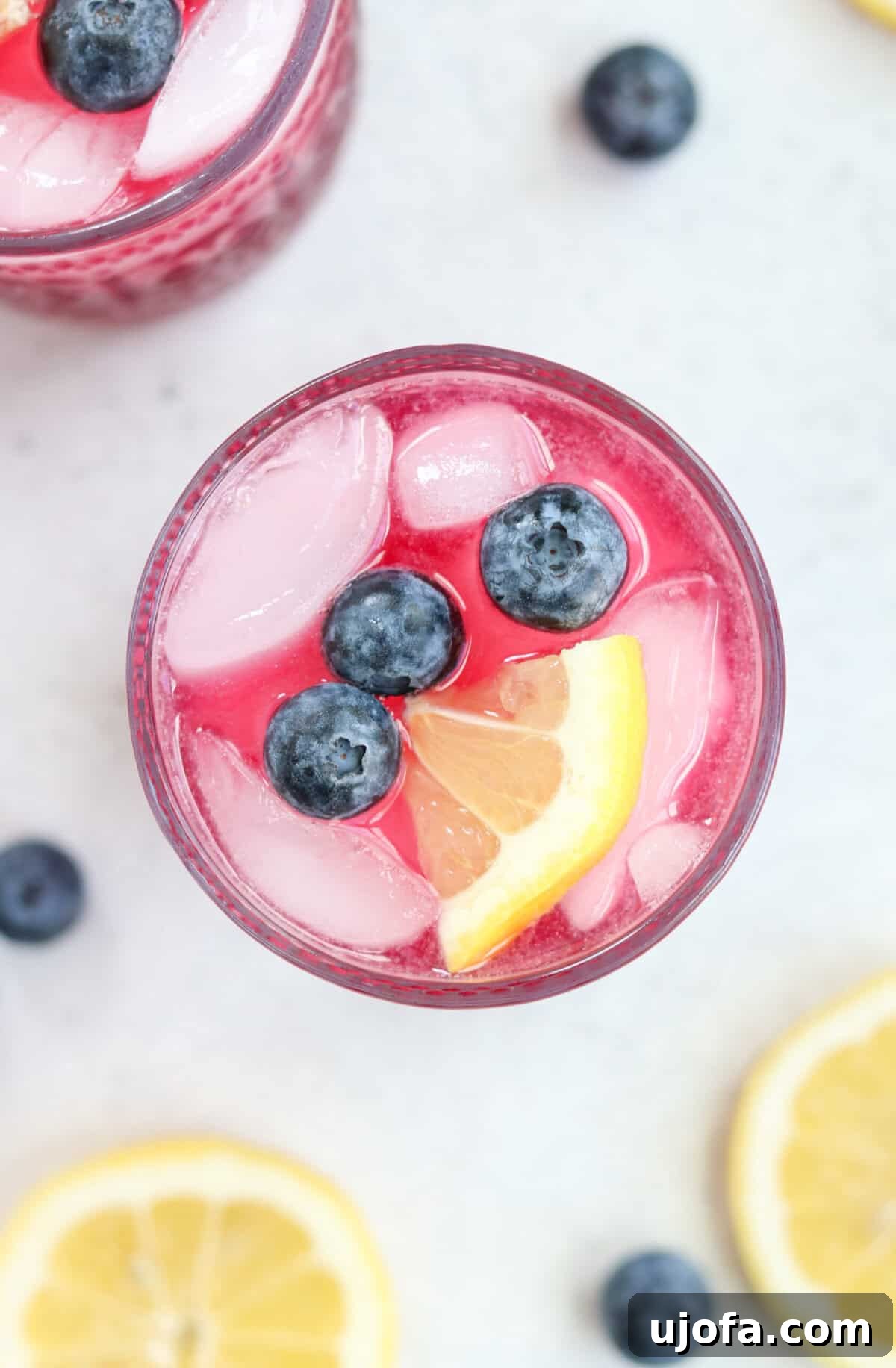 An overhead shot of a delightful lemon blueberry mocktail, adorned with ice cubes, fresh blueberries, and lemon slices.