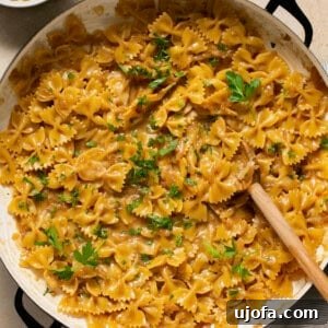 A skillet full of creamy French Onion Pasta, garnished with fresh parsley, ready to be served from the pot.