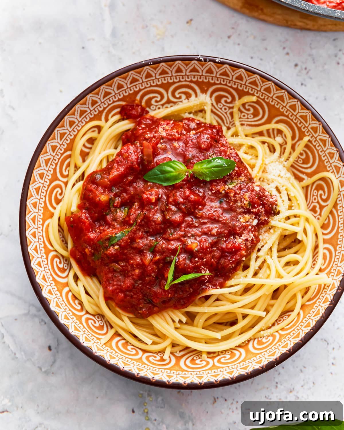 An overhead shot of a bowl of perfectly cooked gluten-free spaghetti generously topped with homemade sauce and fresh basil.