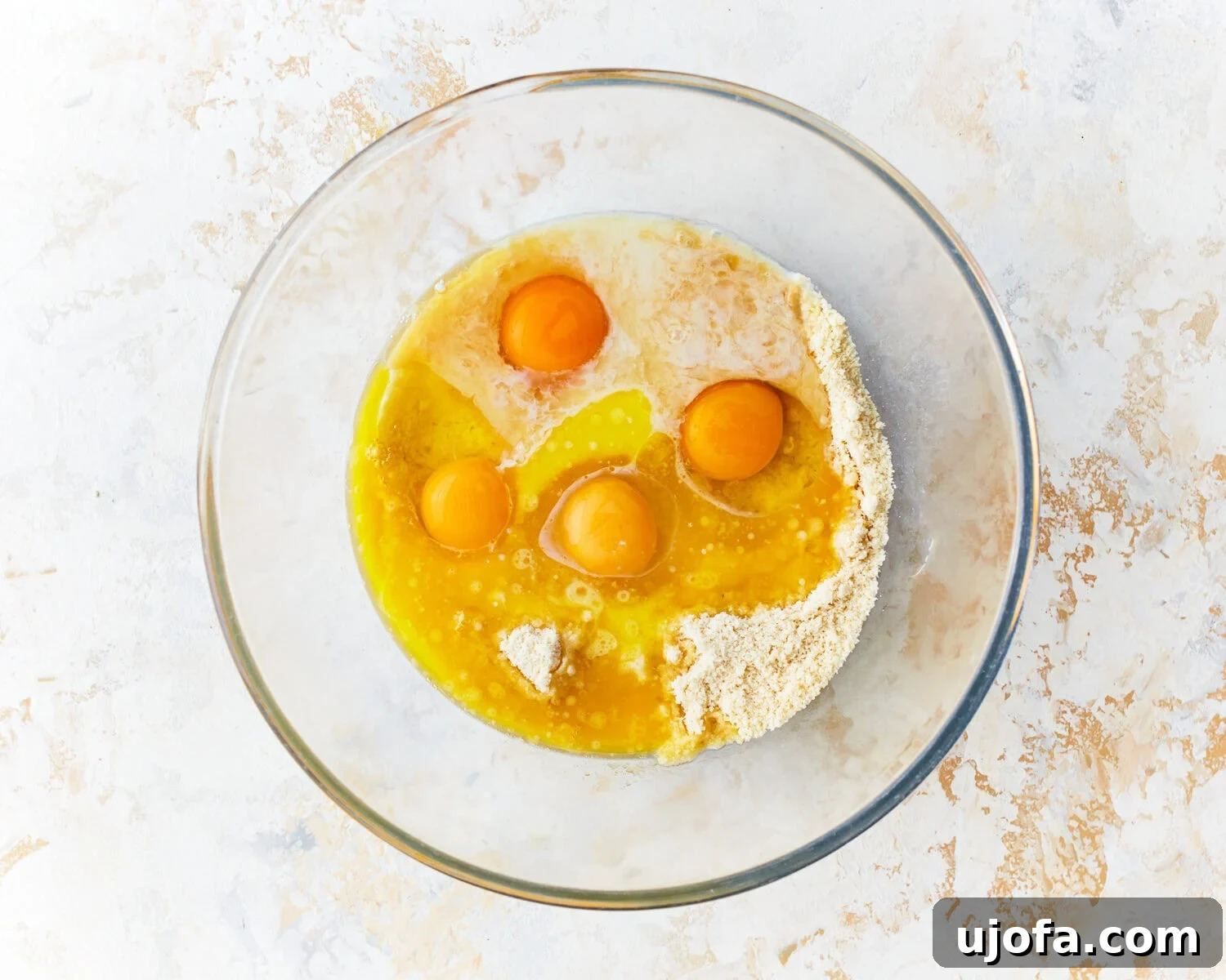 Fluffy Almond Pancakes 6 Eggs and melted butter added to dry ingredients for almond flour pancakes in a glass bowl.