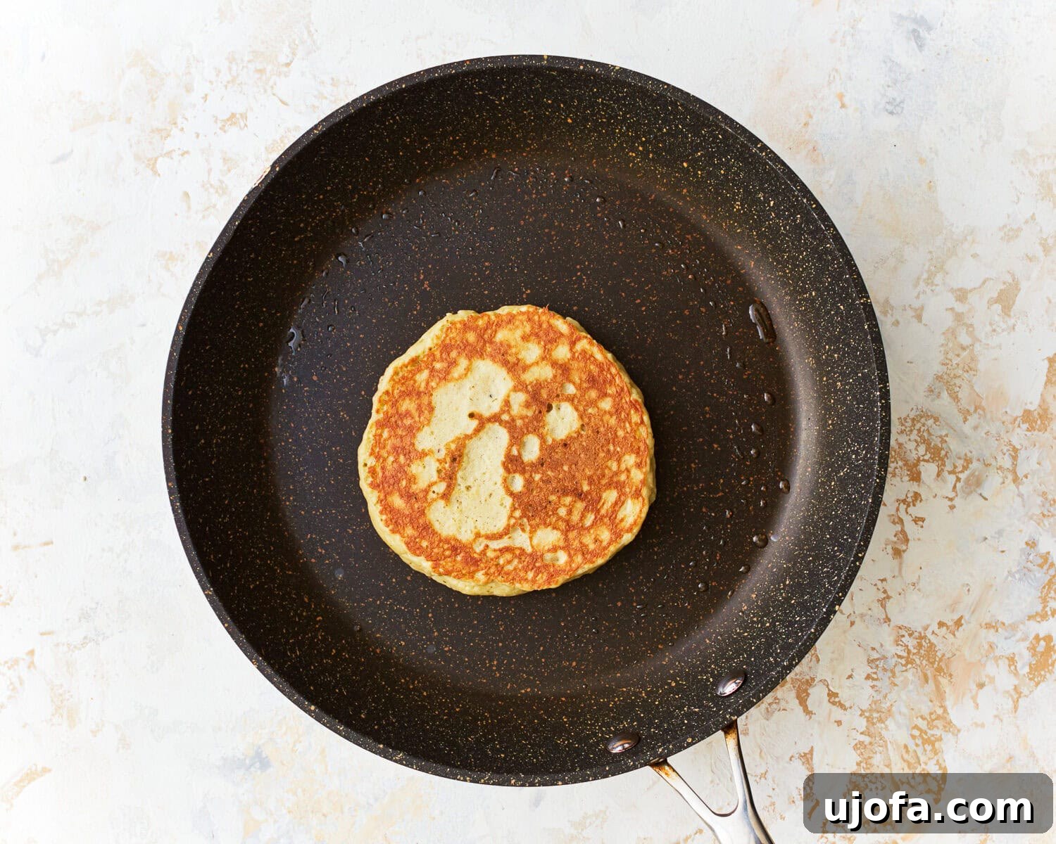 Fluffy Almond Pancakes 9 An almond flour pancake cooking in a frying pan.