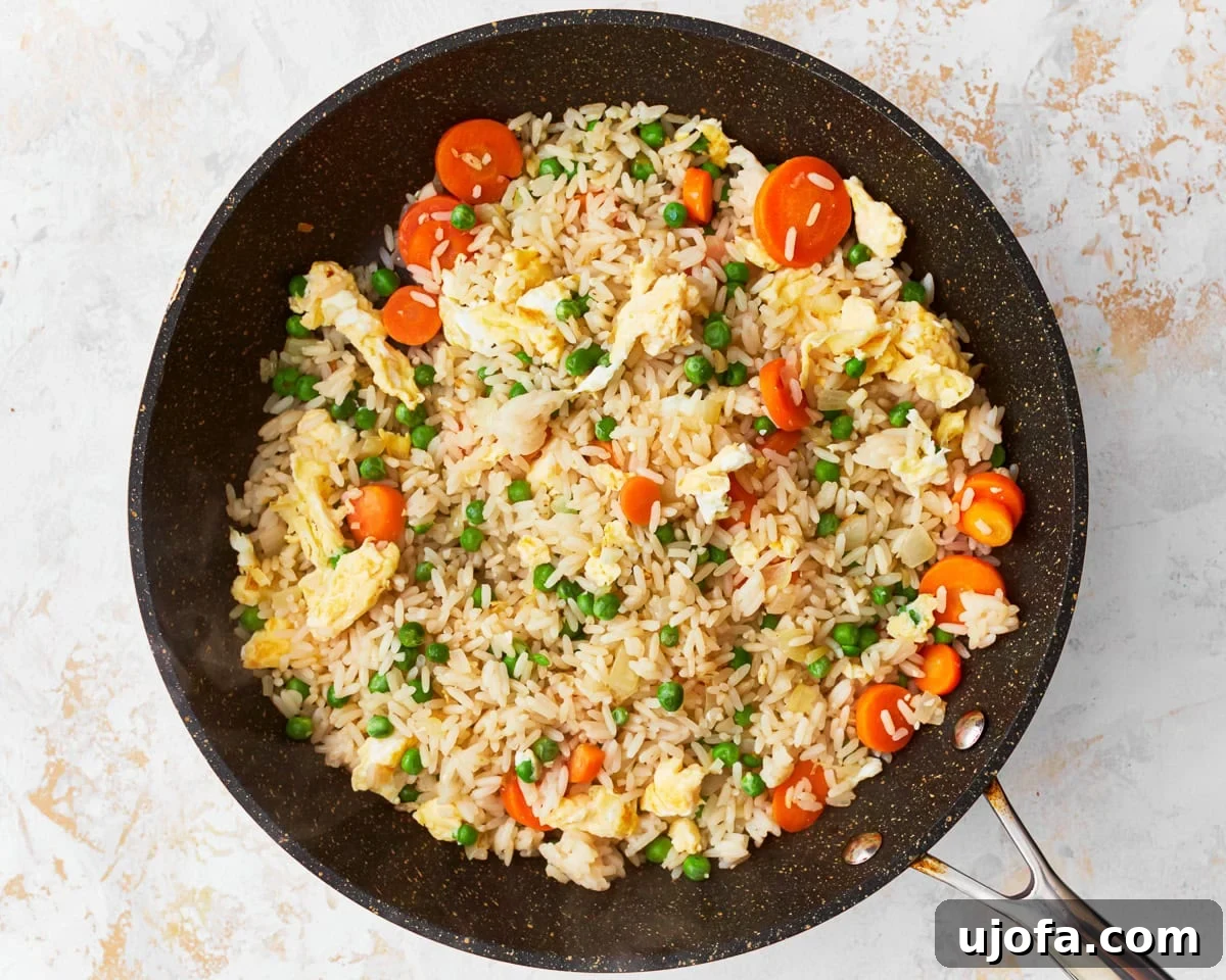 Your New Favorite Gluten-Free Fried Rice 9 Cooked rice, vegetables, and scrambled eggs being stir-fried together in a skillet.