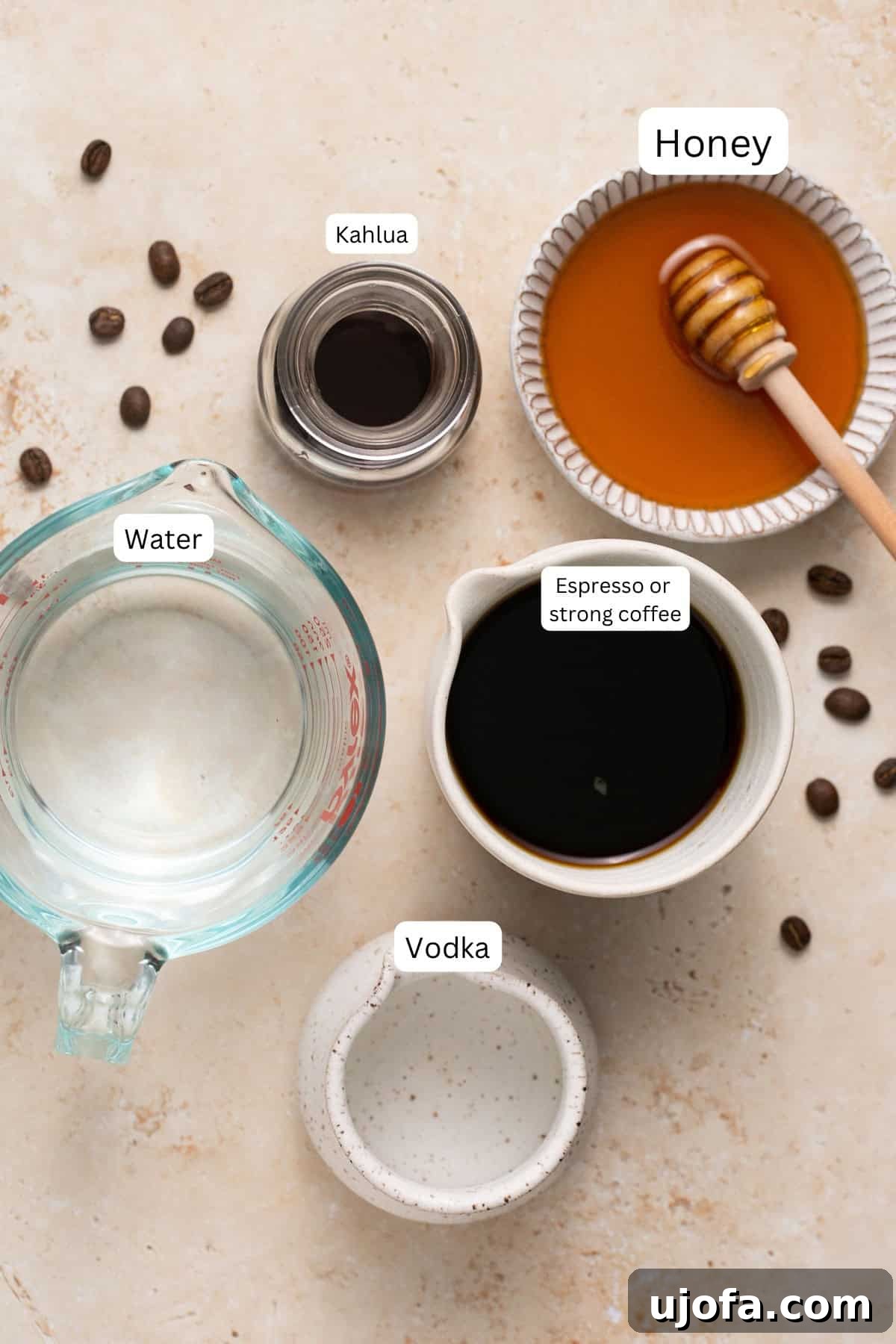 Espresso Martini Perfection Made with Kahlúa 3 A selection of ingredients for an espresso martini recipe, including vodka, coffee liqueur, a bottle of honey, and coffee beans, arranged on a surface.