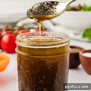 A glass jar of gluten-free balsamic vinaigrette with a spoon, ready to be served.