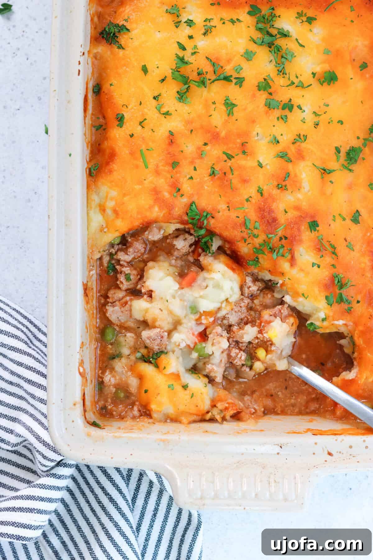 Savory Turkey Shepherd's Bake 6 shepherd's pie in a casserole dish with a scoop being taken out
