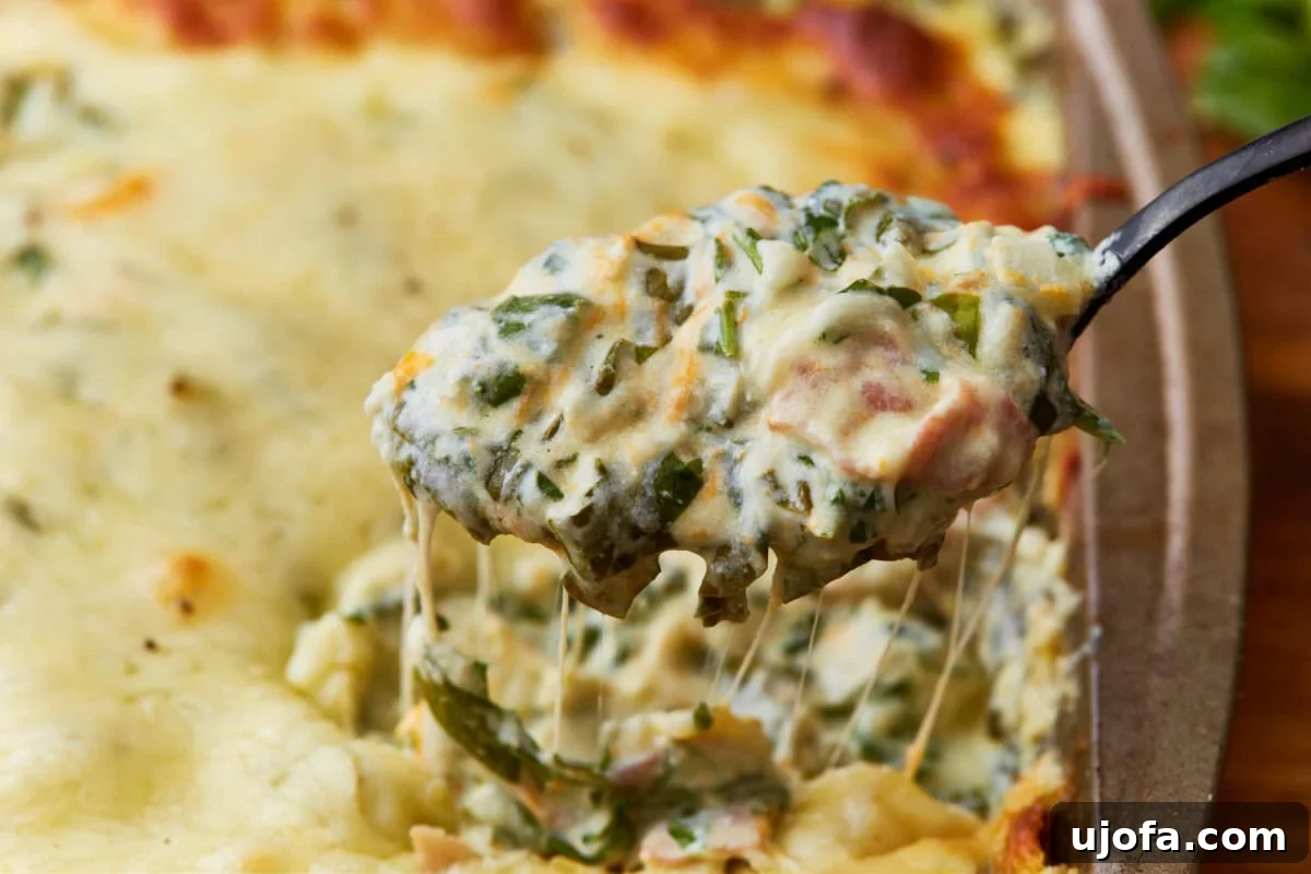 Velvety Warm Spinach Indulgence 11 spoon scooping out hot spinach dip from a baking dish
