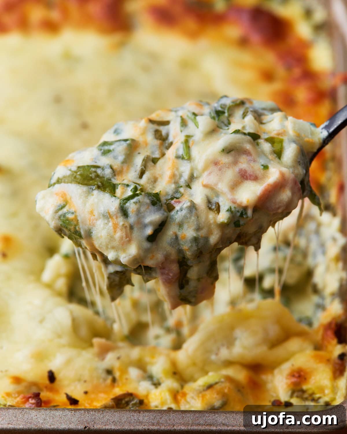 Velvety Warm Spinach Indulgence 5 spoon scooping out some hot spinach dip out of a baking tin