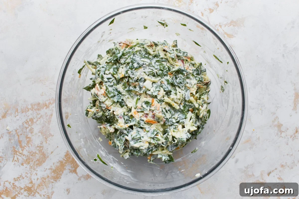 Velvety Warm Spinach Indulgence 8 hot spinach dip filling mixed in glass bowl resting on light surface