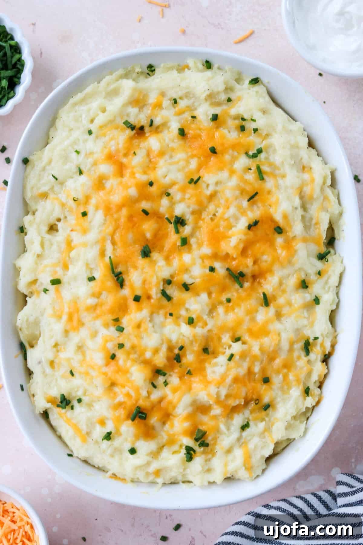 Seriously Cheesy Mash 6 A close-up of cheesy mashed potatoes in a casserole dish, topped with freshly chopped green chives for garnish, ready to be served.
