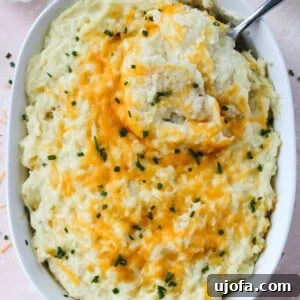 cheesy mashed potatoes in a casserole dish with a spoon taking a scoop out