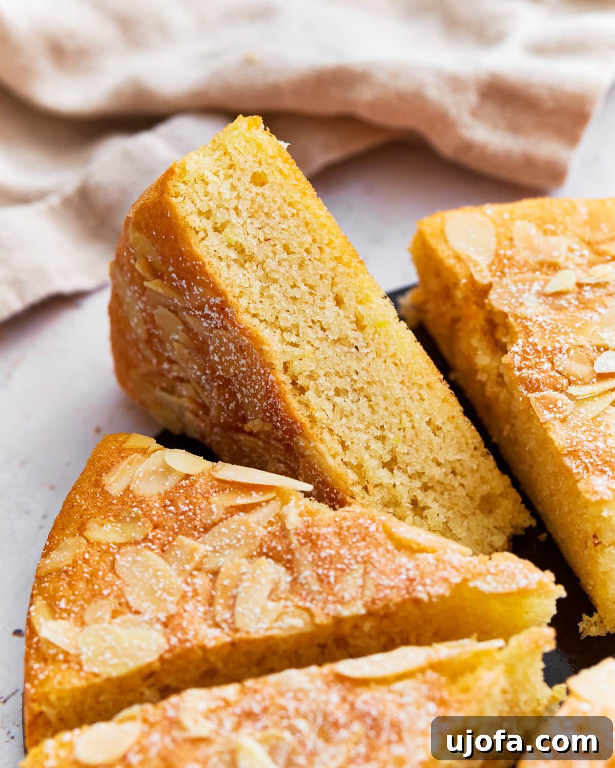 Tender Almond Flour Cake 5 Several slices of almond flour cake arranged neatly on a serving tray, garnished with powdered sugar.