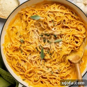 Pumpkin pasta sauce with spaghetti in a pan with a wooden spoon topped with sage