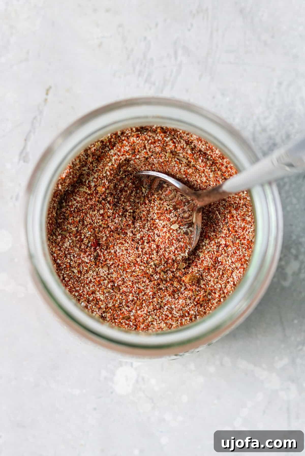 Fiesta Chicken Taco Blend 2 A glass jar holding homemade chicken taco seasoning with a silver spoon, ready for use.