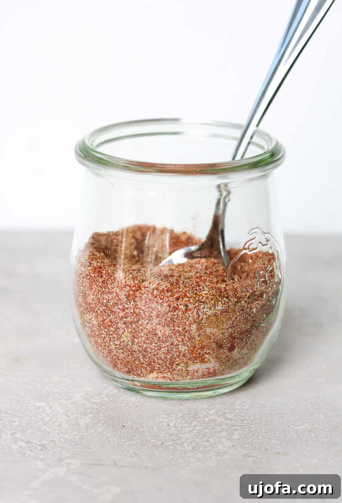 Fiesta Chicken Taco Blend 5 Various spices in a glass jar with a spoon, ready for cooking.