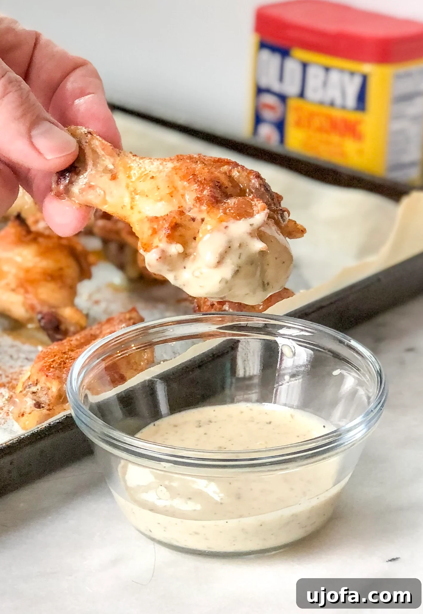 Crispy Old Bay Wing being dipped in ranch dressing, showcasing its golden-brown crispiness