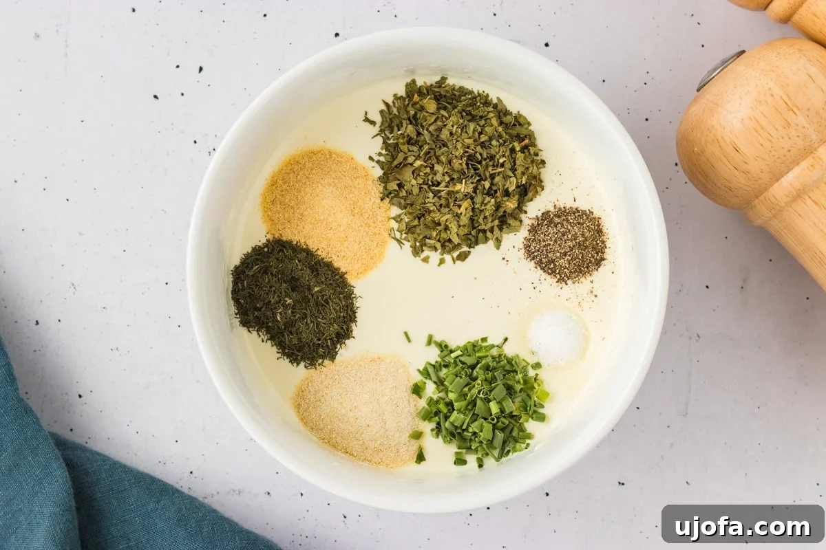 Luscious Plant-Based Ranch 6 Overhead view of a bowl filled with dairy-free ranch base topped with piles of dried herbs and spices, ready to be mixed.