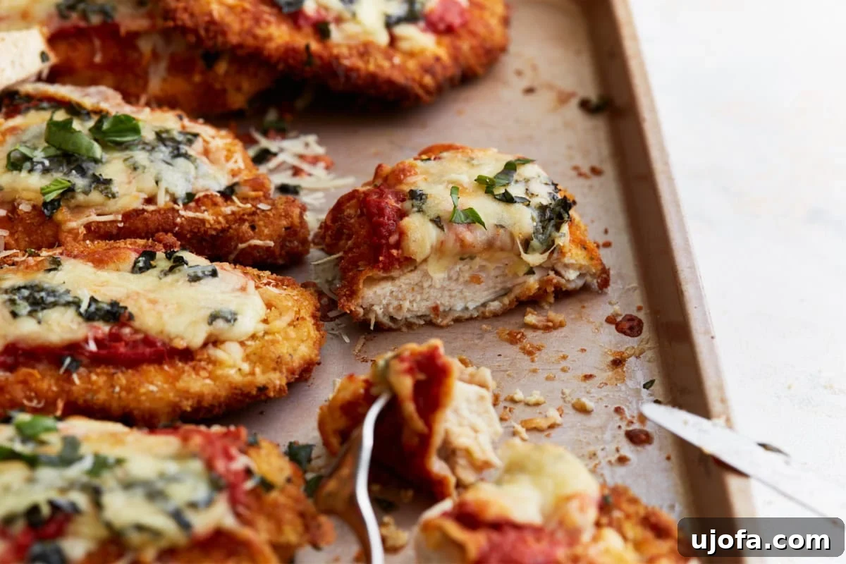 Irresistible Gluten-Free Chicken Parm 16 A perfectly sliced piece of gluten-free chicken parmesan, revealing the juicy chicken, crispy coating, and layers of melted cheese and sauce, garnished with fresh basil.
