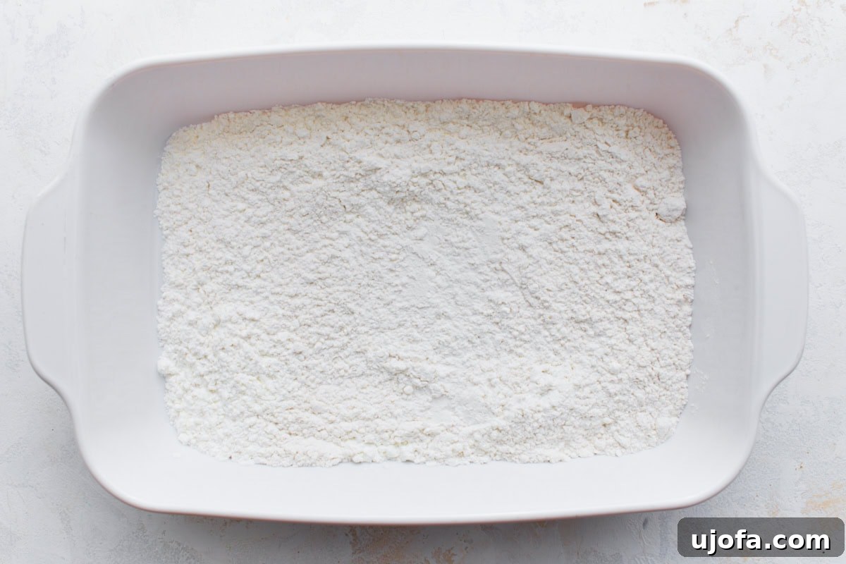 Irresistible Gluten-Free Chicken Parm 6 A white baking dish containing a mixture of gluten-free flour and cornstarch.