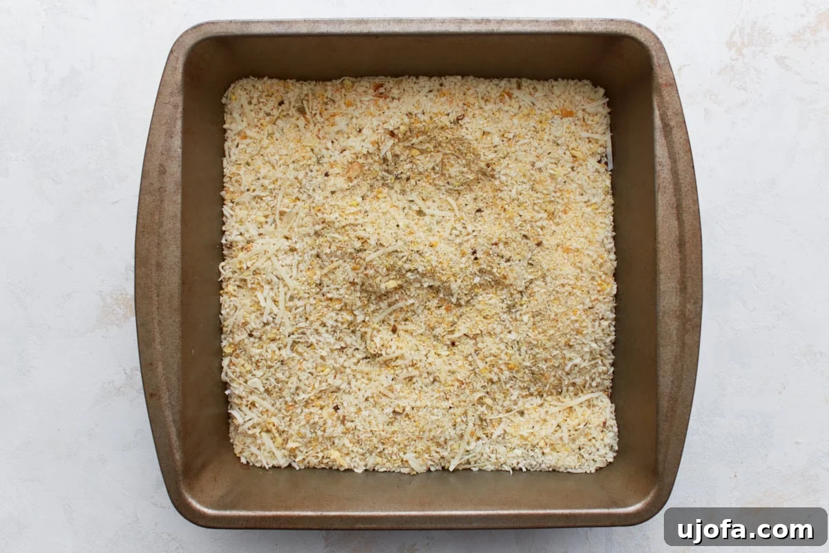 Irresistible Gluten-Free Chicken Parm 7 A stainless steel dish filled with a seasoned blend of gluten-free panko, regular gluten-free breadcrumbs, Parmesan cheese, garlic powder, onion powder, and Italian seasoning.