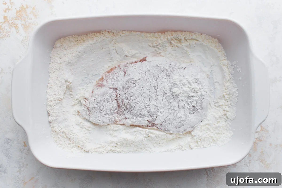 Irresistible Gluten-Free Chicken Parm 8 A raw chicken breast fully dredged in the gluten-free flour mixture, showcasing an even coating.