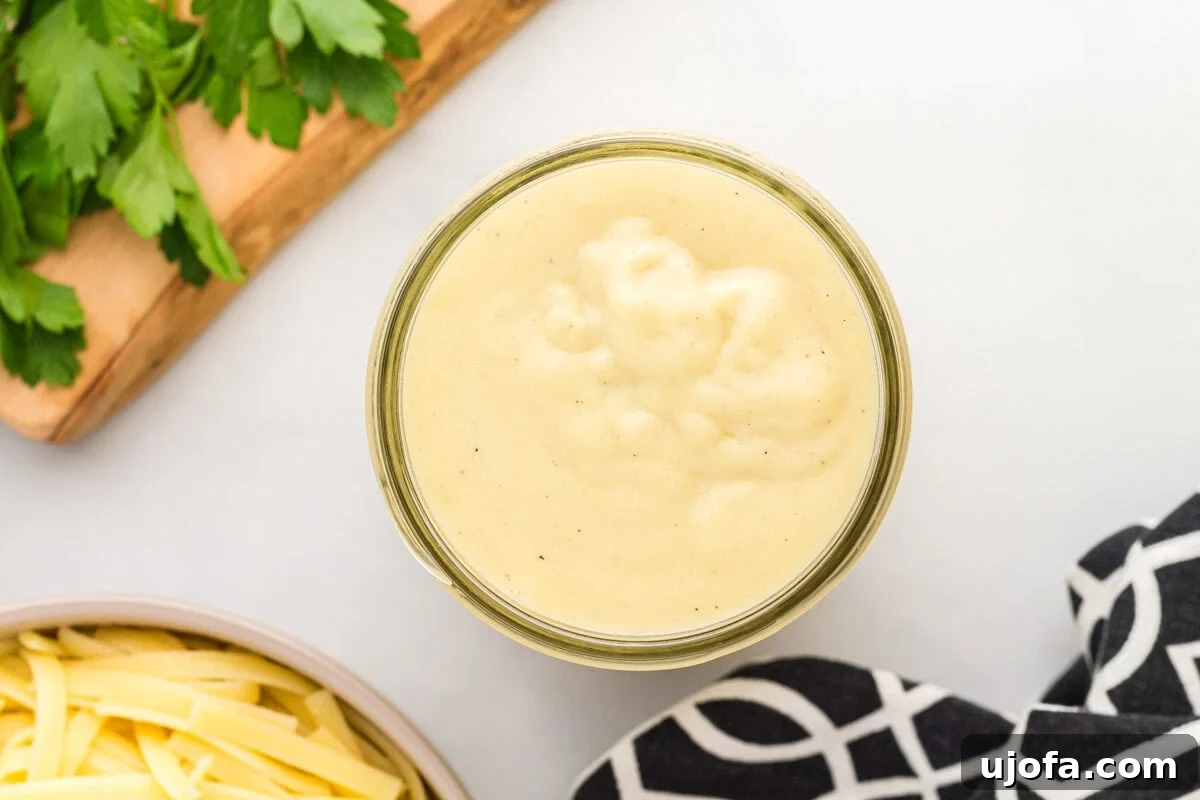 Velvety Plant-Based Alfredo 11 Thickened dairy-free Alfredo sauce resting in a white bowl, garnished with fresh herbs, ready for serving.